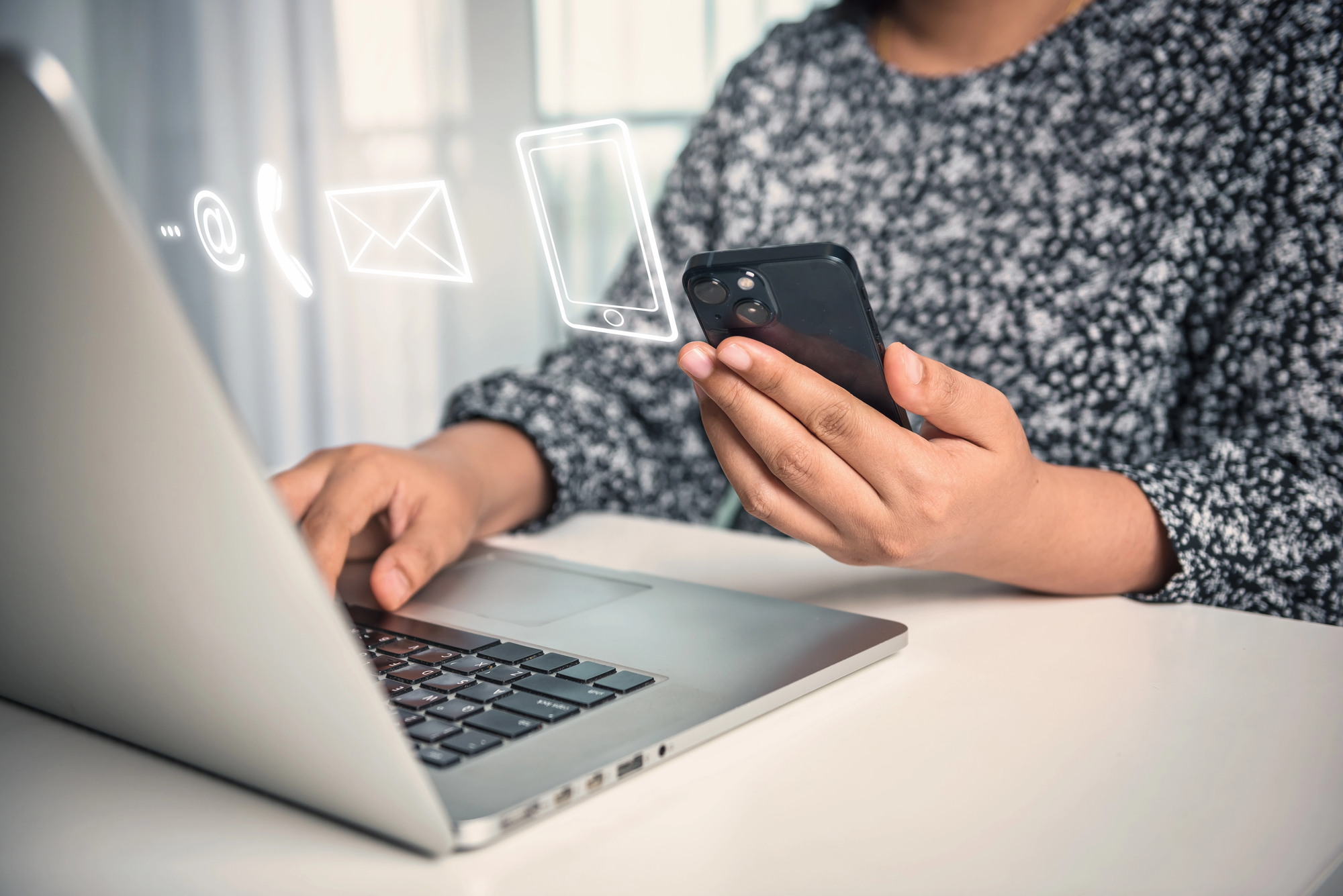 Frau bedient Laptop darüber sind digitale Icons zur Kundenkommunikation zu sehen